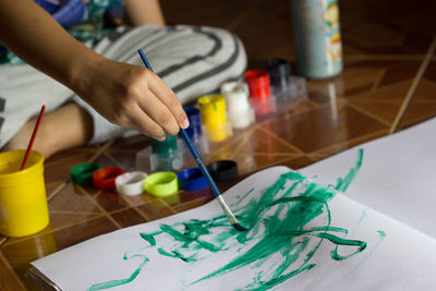 Midsection of boy painting on paper while sitting at home