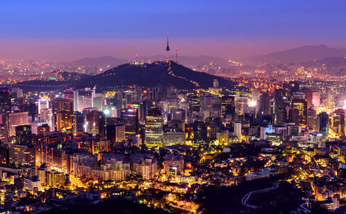 Illuminated cityscape against sky at night