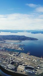 Aerial view of city by sea against sky