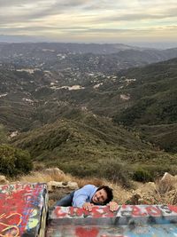 High angle view of woman lying on landscape against sky