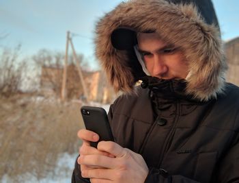 Midsection of man using mobile phone in snow