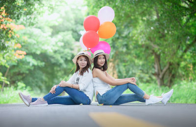 Portrait of women with balloons sitting on road