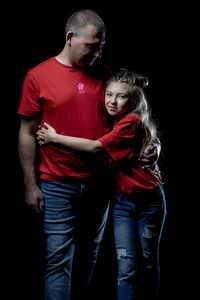 Full length of father and daughter against black background