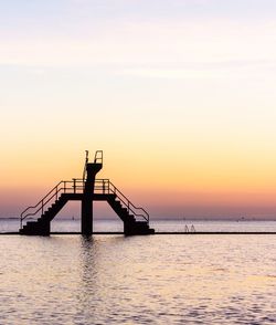 Silhouette pier over sea against sky during sunset