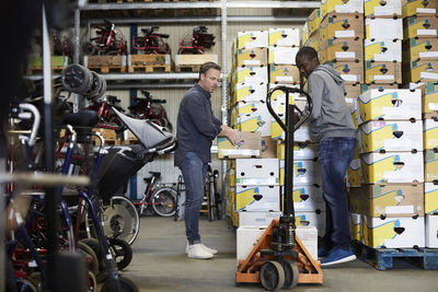 Full length of male volunteers stacking boxes at warehouse