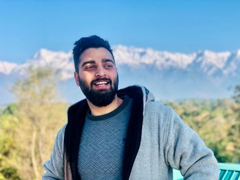 Portrait of young man standing against sky