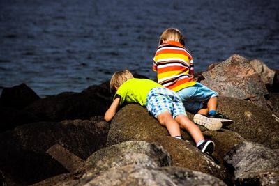 Brothers on rock at beach