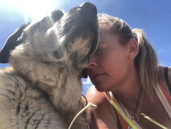 Close-up of woman with dog against sky