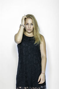 Portrait of young woman standing against white background