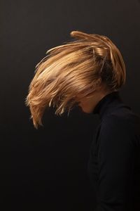 Side view of woman standing against black background