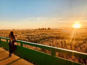 Woman on field against sky during sunset