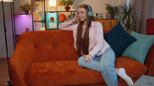 Portrait of young woman sitting on sofa at home