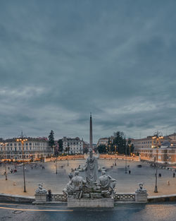 Statue in city against cloudy sky