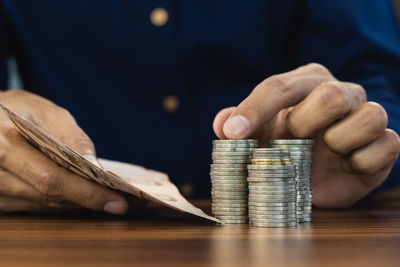 Close-up of hand holding coins on table