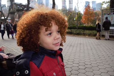 Close-up of boy with curly hair looking away on footpath