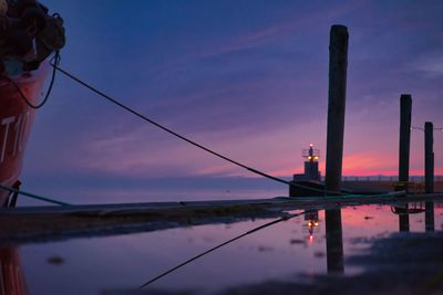 Reflection of wooden post in lake at sunset