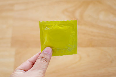 Close-up of man holding condom on table