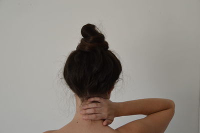 Rear view of woman with hands behind head against white background