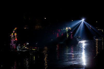 Illuminated lights in river against sky at night