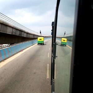 Reflection of rickshaw on bus by flyover