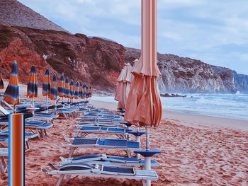 Chairs on beach against sky