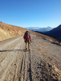 Man walking on mountain against clear blue sky