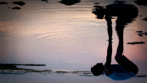 Low section of silhouette man at beach against sky during sunset