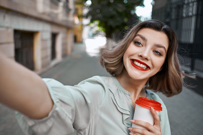 Portrait of a smiling young woman holding camera