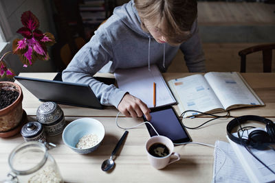 High angle view of teenage boy using digital tablet while studying on table at home