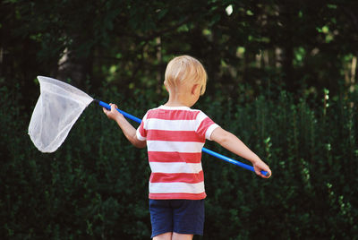 Rear view of boy holding butterfly net