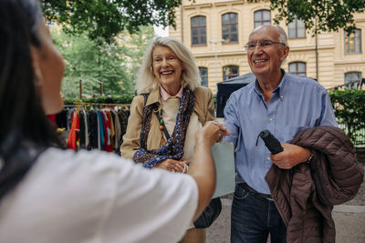 Owner giving shopping bag to senior customers at market