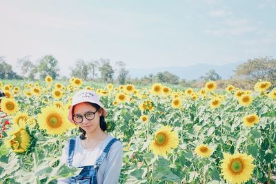 Low angle view of woman standing on sunflower field