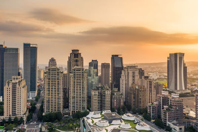 Modern buildings in city against sky during sunset