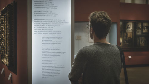 Rear view of man looking at notice board