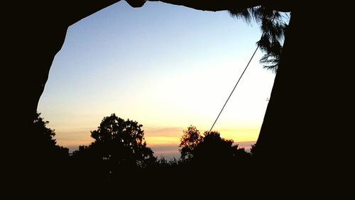 Silhouette trees against clear sky during sunset