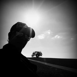 Silhouette man hand by tree against sky