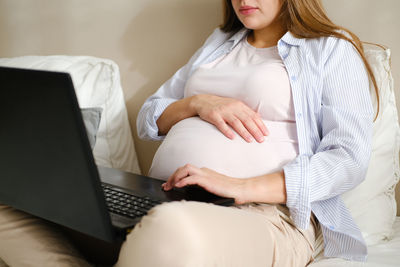 Midsection of woman using laptop at home