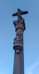 Low angle view of cross statue against blue sky