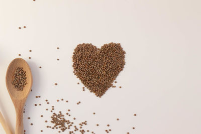 Heart made of raw lentils on a white background with kitchen utensils