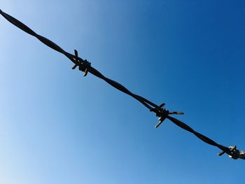 Low angle view of barbed wire against clear sky