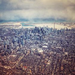 High angle view of city buildings against cloudy sky