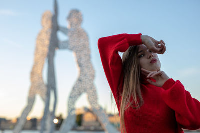 Portrait of young woman standing against clear sky
