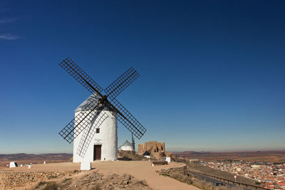 Traditional windmill on landscape against clear blue sky