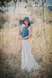 Portrait of smiling young woman standing on grassy field