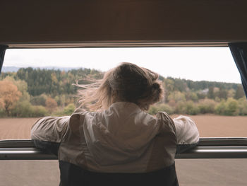 Rear view of woman looking through window