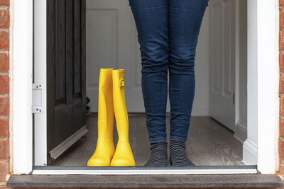 Legs of woman standing with rubber boot at home during rainy season