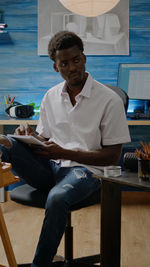 Young man using mobile phone while sitting on table