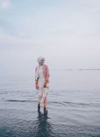 Woman wading in sea against sky