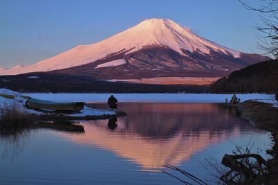 Scenic view of person at calm lake against cloudy sky