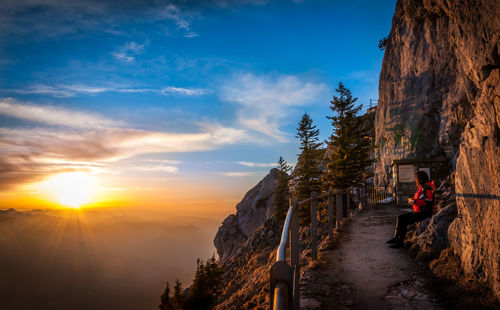 Man on mountain road against sky during sunset